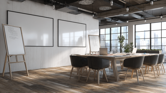 Modern office meeting room with two wall-mounted whiteboards and wooden easels holding presentation boards, surrounded by chairs and large windows with city view.